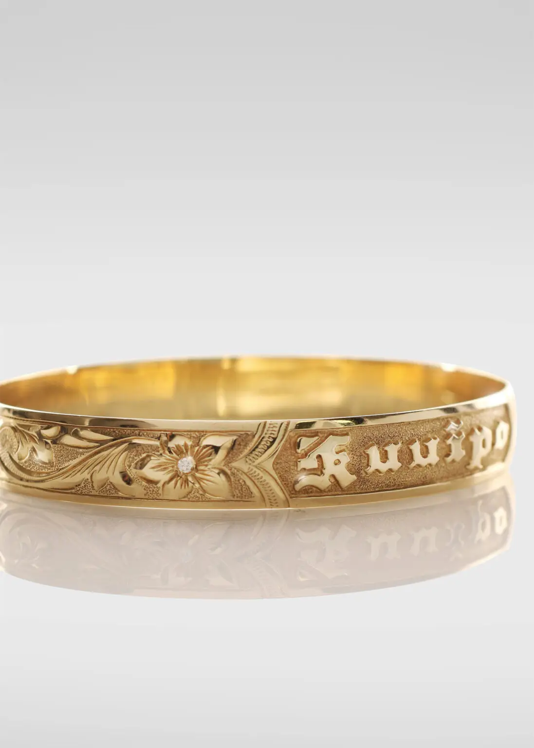 Smooth edge 14K gold Hawaiian heirloom bracelet with diamond centered flower and "Kuuipo" raised lettering.