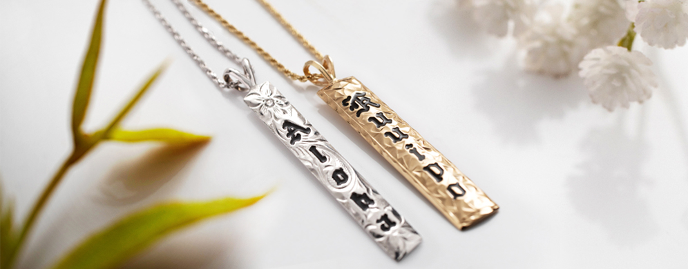 Two vertical Hawaiian pendants in 14K white and yellow gold.