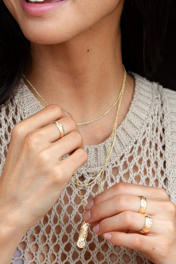 Various personalized Hawaiian heirloom jewelry on model. Includes Hawaiian rings and a vertical pendant.
